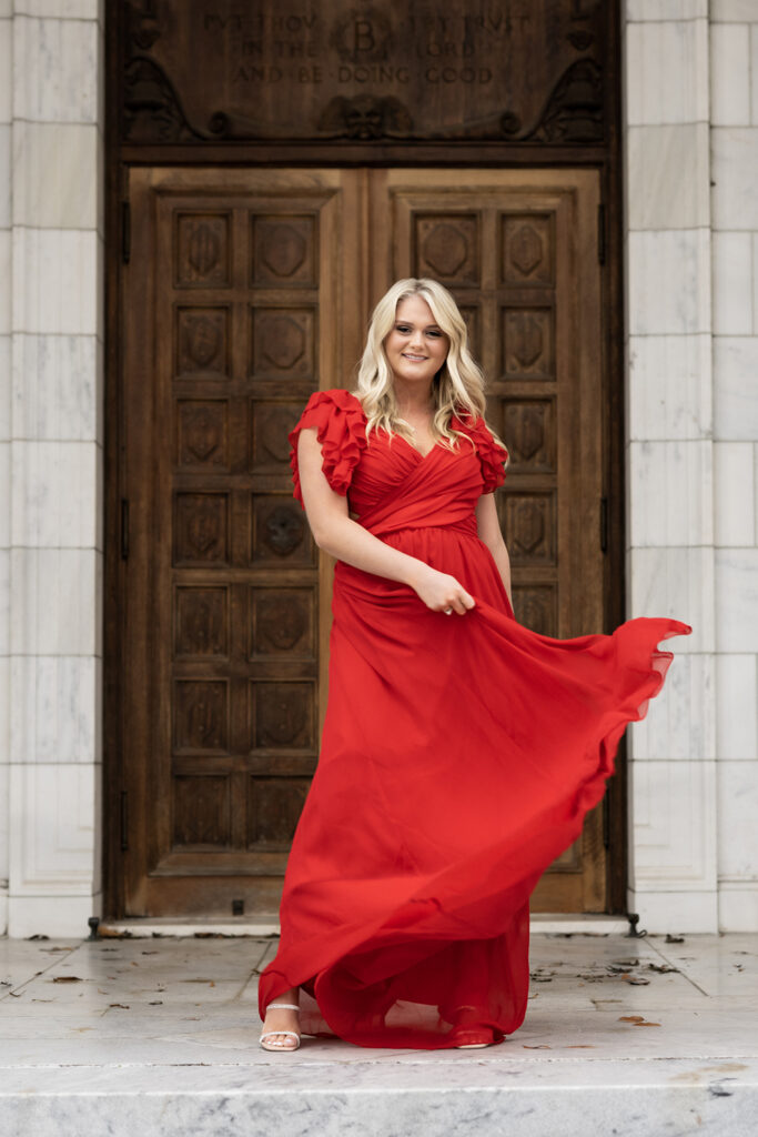 girl in long red dress at brooks museum for senior photoshoot