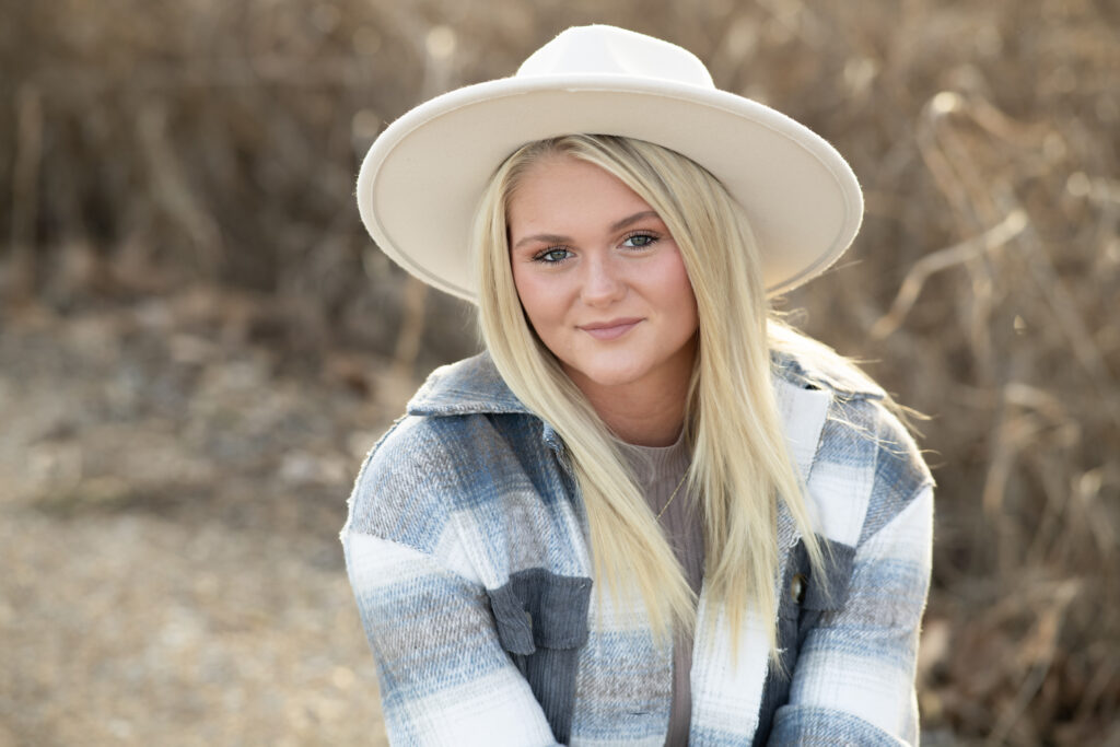 Closeup portrait of high school senior during outdoor nature photoshoot with white hat on