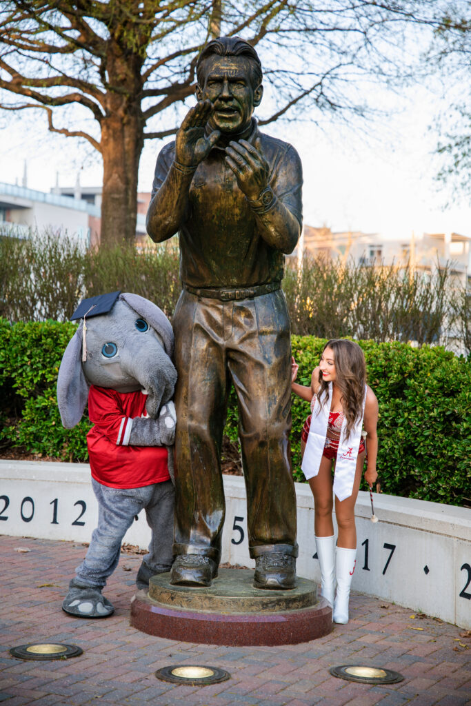 Albama mascot Big AL peeks around the Nick Saban statue at Alabama graduate and Crimsonette at her grad session with Chris Landau Photography Alabama grad photographer.