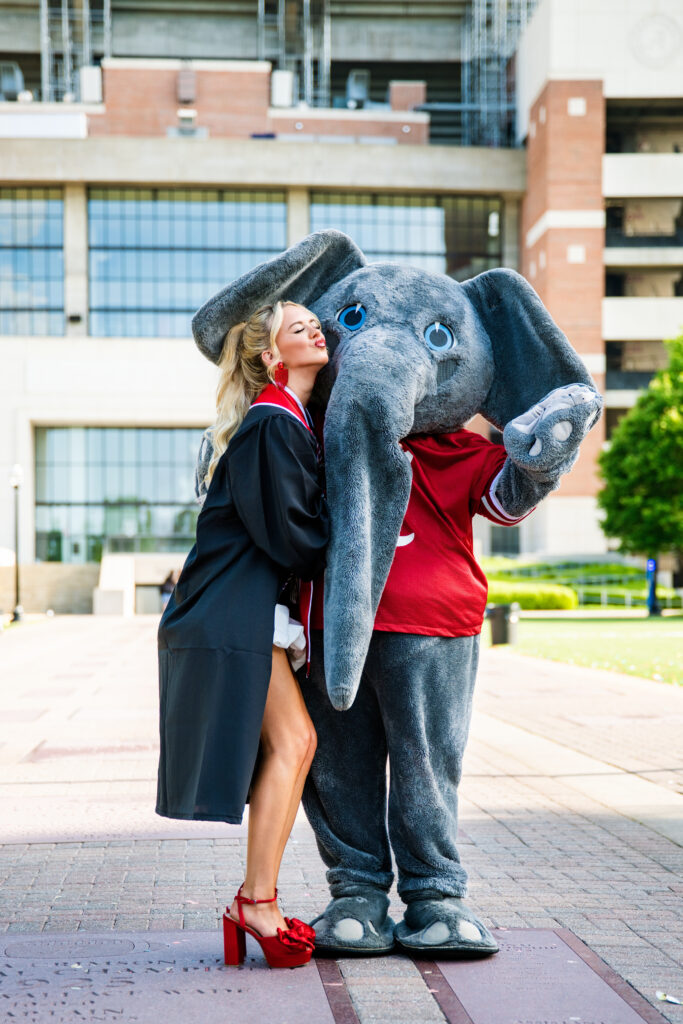 Alabama mascot Big AL poses with Alabama graduate at her grad photoshoot with Chris landau Photography. The grad is pretending to give Big AL a kiss. Alabama grad photographer