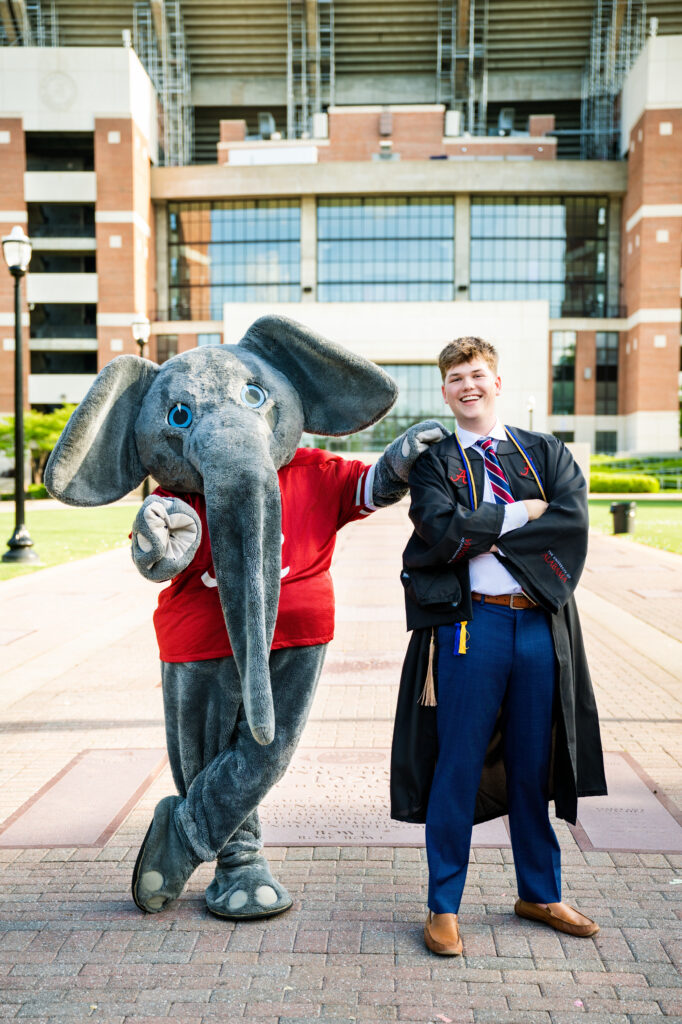 Alabama mascot Big AL poses with Alabama graduate at his grad photoshoot with Chris landau Photography. They are posing in front of Bryant Denny stadium on the Walk of Champions. Alabama grad photographer