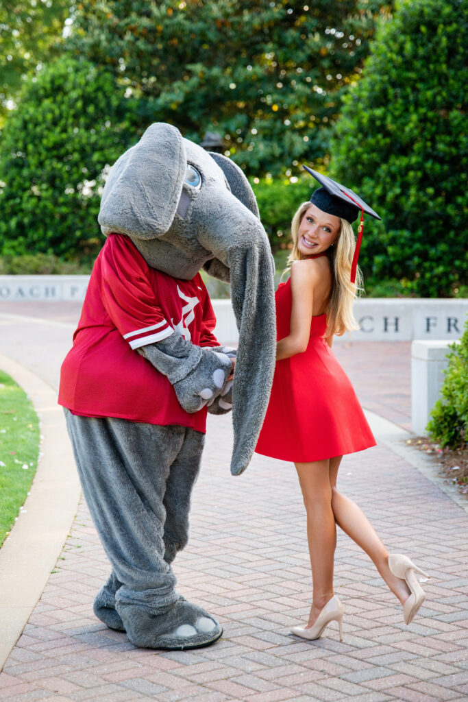 Alabama mascot Big AL holds hands with an Alabama graduate at her graduation photoshoot with Chris Landau Photography Alabama grad photographer.