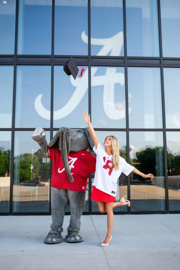 Alabama mascot Big AL and an Alabama graduate throw a graduation cap in the air and look at it during a graduation photoshoot with Chris landau Photography Alabama grad photographer