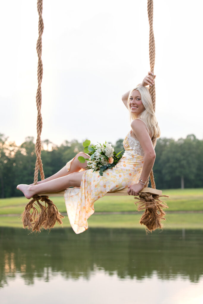 High school senior photoshoot with girl in swing over water