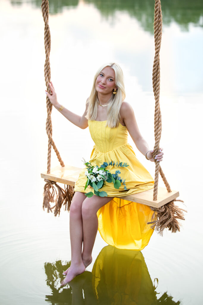 High school senior photoshoot with girl in swing over water