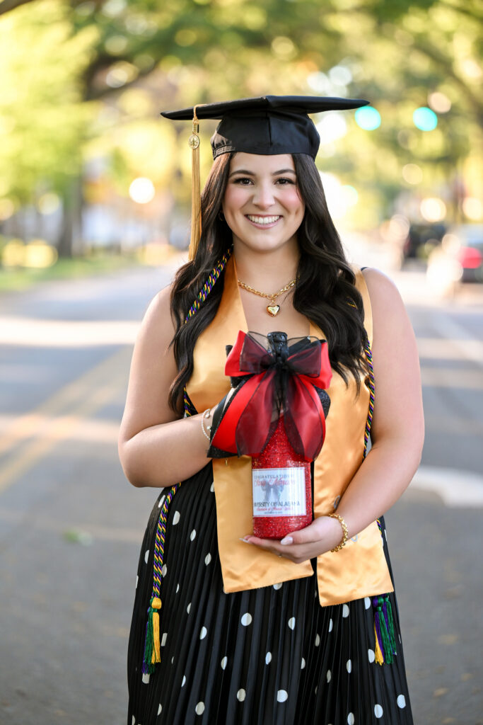 Bama grad holds custom champagne bottle at her grad session