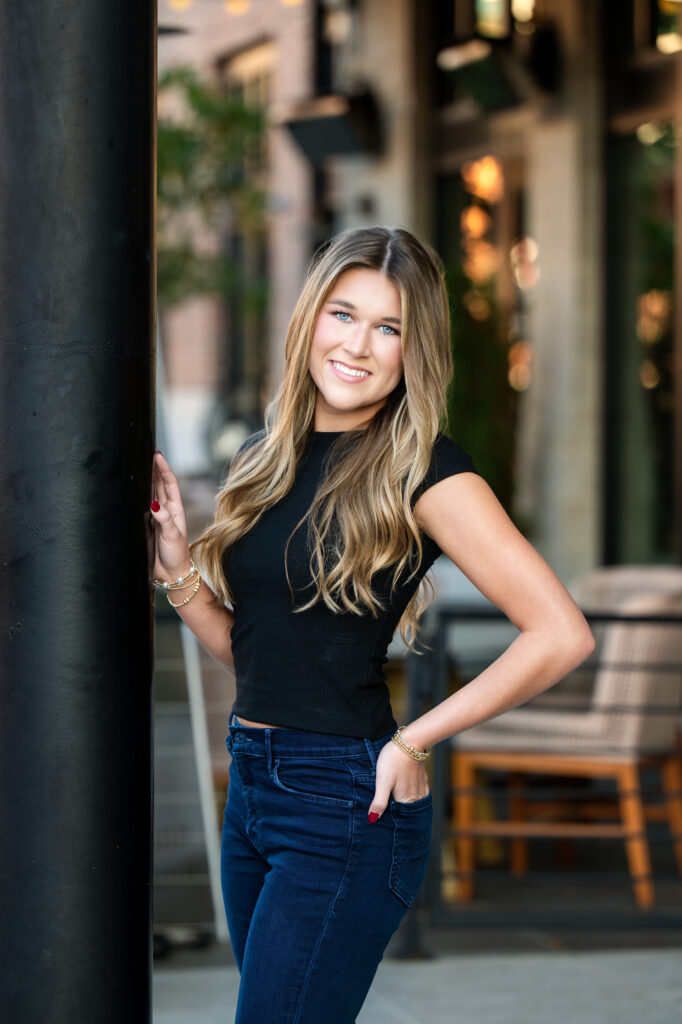 High School senior poses leaning on a pole Downtown Tuscaloosa during a photoshoot with Chris Landau Photography. 