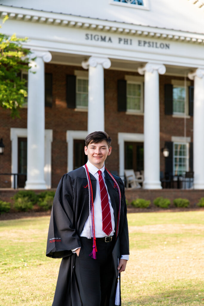 Alabama grad stands in front of his fraternity house during his grad photoshoot with Chris Landau