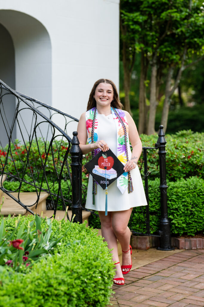 Education major leans on the railing at the President's Mansion steps during her grad photoshoot with Chris Landau Photography